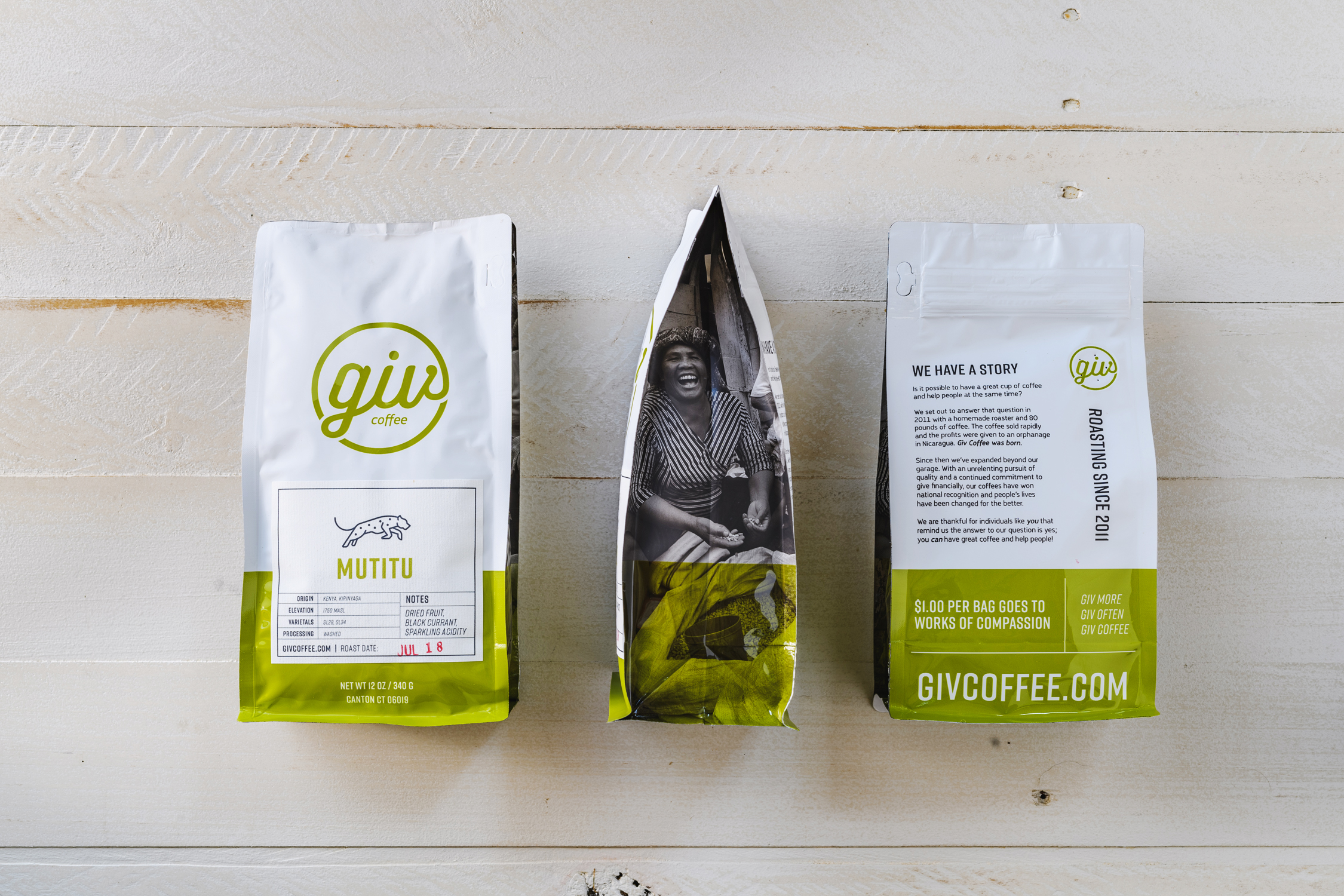 Three Giv Coffee bags on a white wood backdrop: two showing front/back design (white with lime green, handwritten logo, bold font), and one open bag revealing a photo and green coffee beans, emphasizing sourcing.