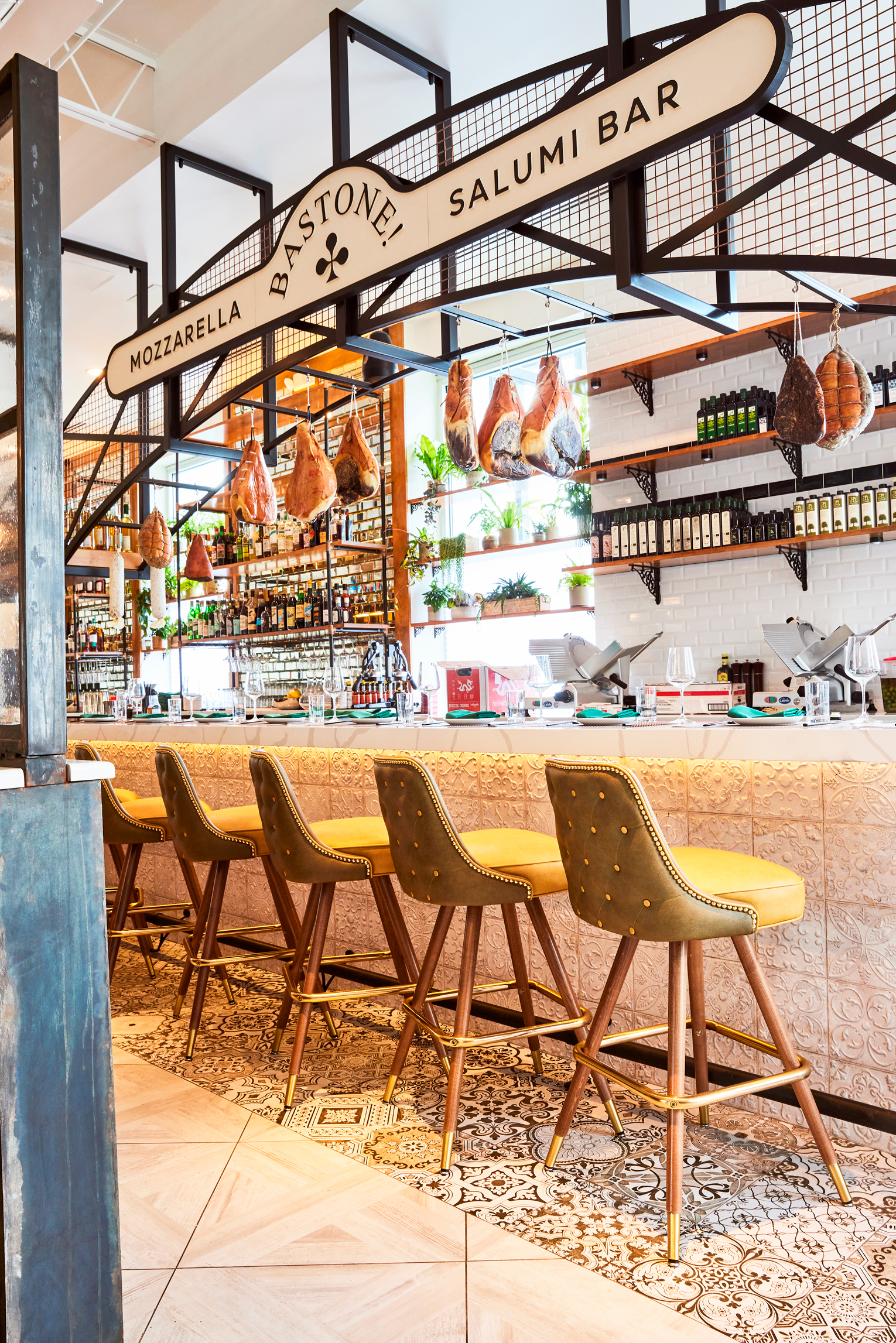 Photo of the Bastone! Mozzarella Bar interior, featuring a stylish bar area with hanging meats, cheeses, and inviting seating.