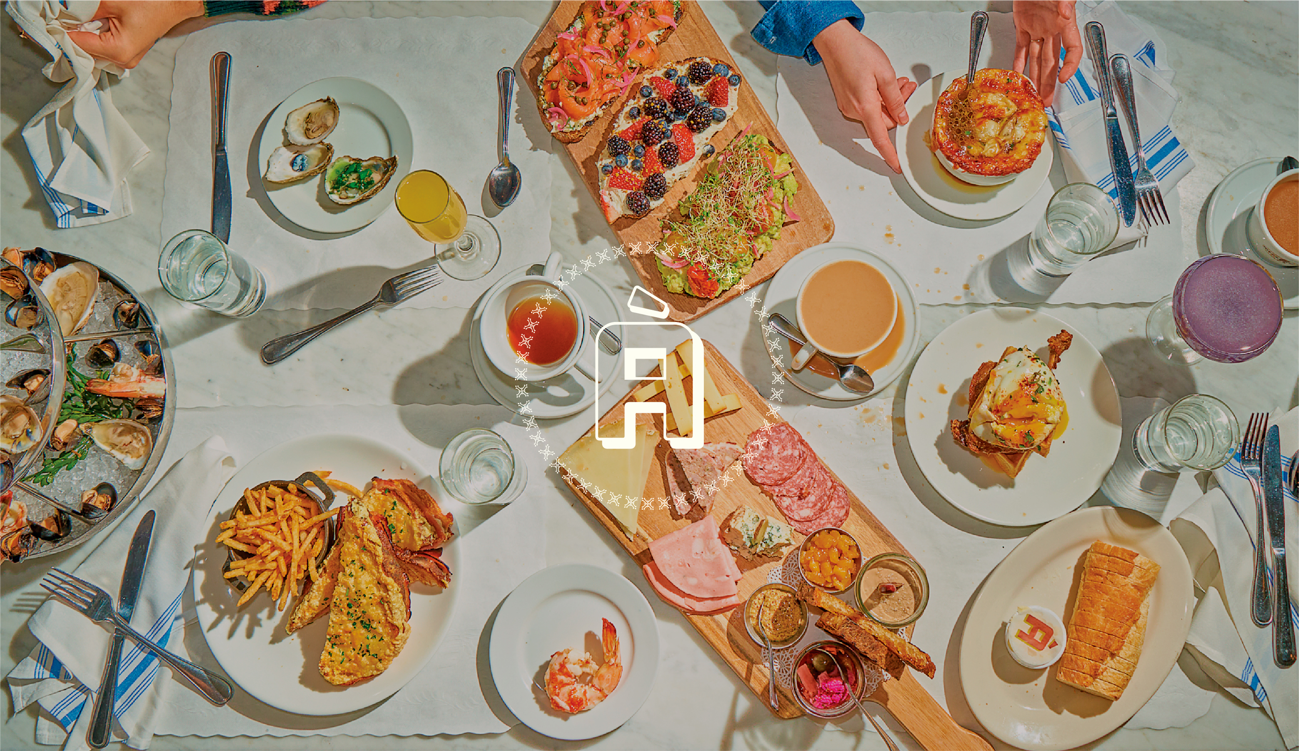 Overhead flat lay composition of a vibrant brunch table spread, with the logo for Åvert Brasserie. Diverse dishes are arranged on a white tablecloth, creating a dynamic interplay of textures and colors.