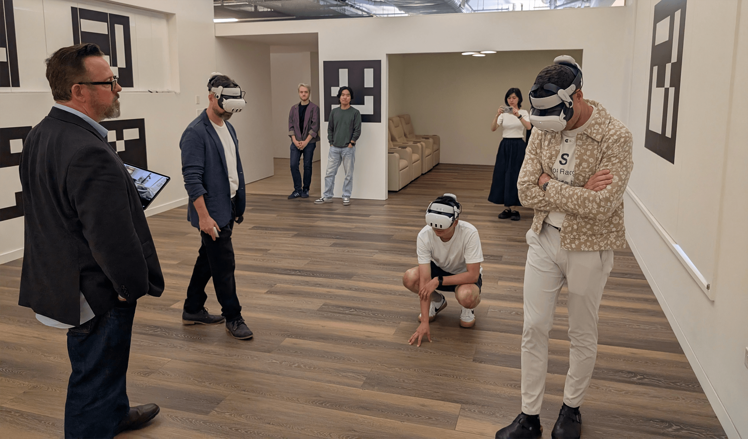 An installation of Agile Lens' Holodeck Anywhere at DBOX offices in New York City.  Three people are looking around wearing VR headsets while a fourth observes using a spectator tablet. 