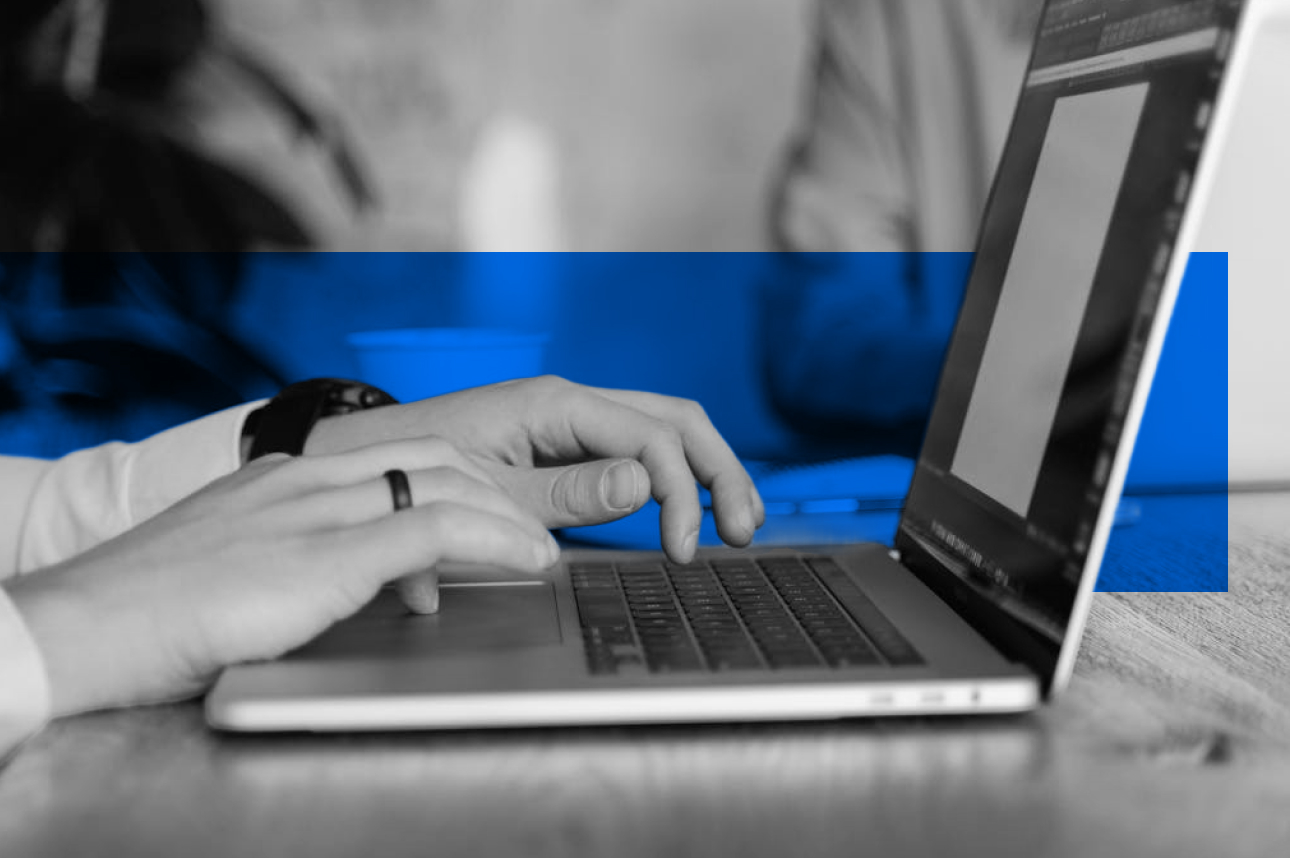 Hands typing on laptop keyboard with blue background accent