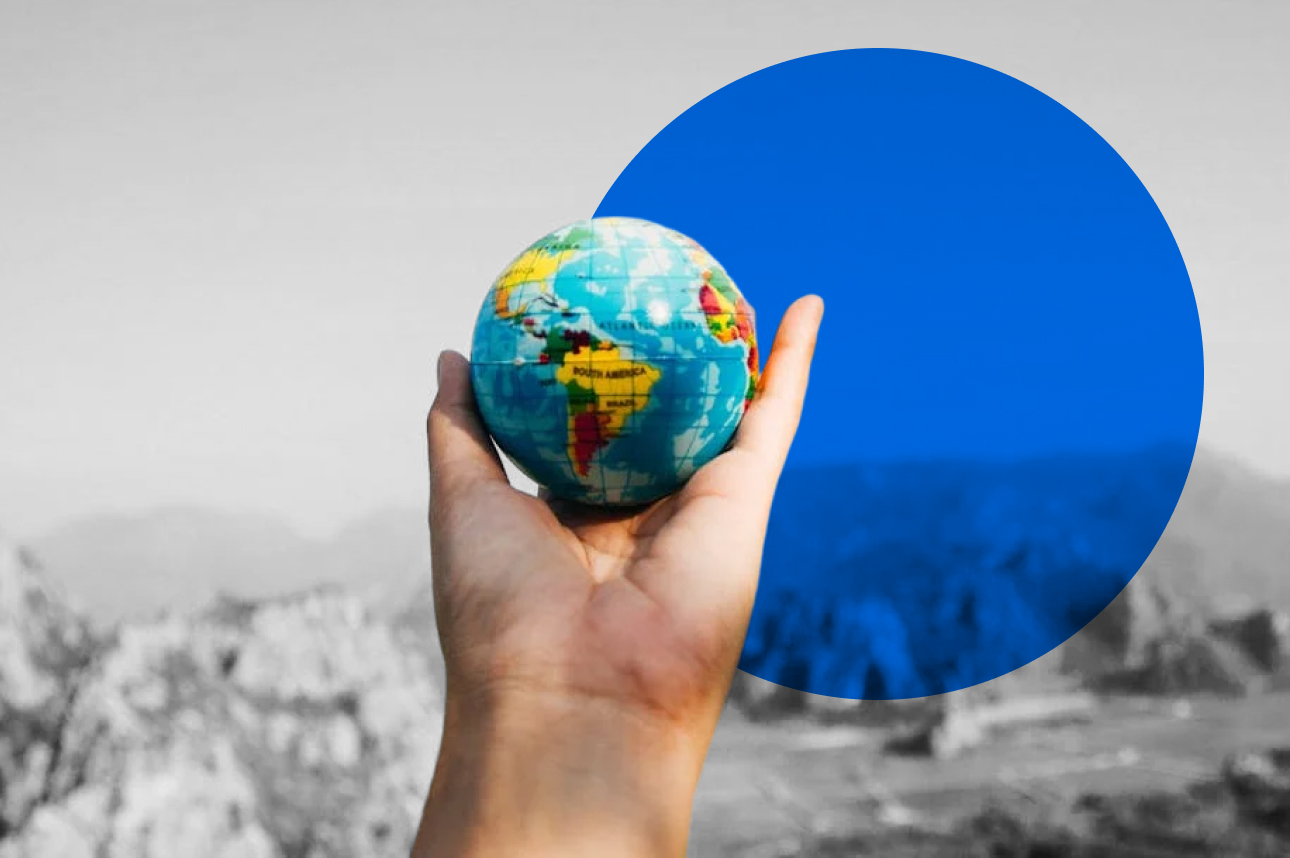 Hand holding small globe with blue background, symbolizing global connectivity