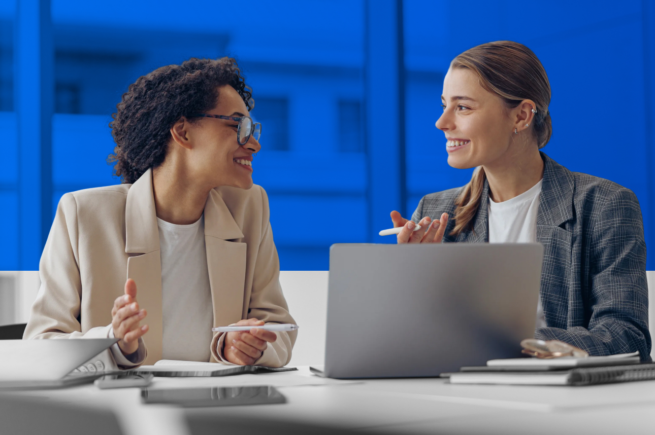 Two professionals smiling and collaborating in an office with blue background