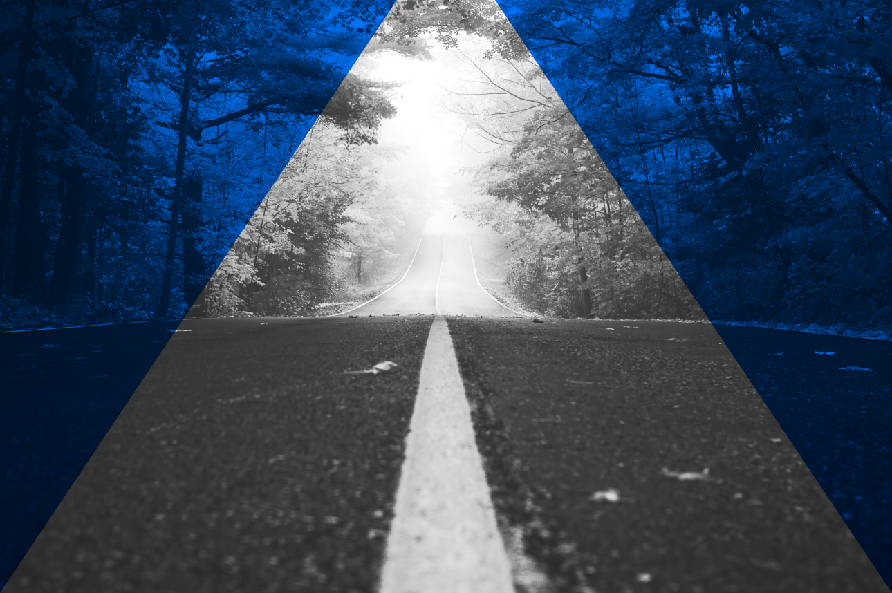 Empty road through misty forest with bright light at the end