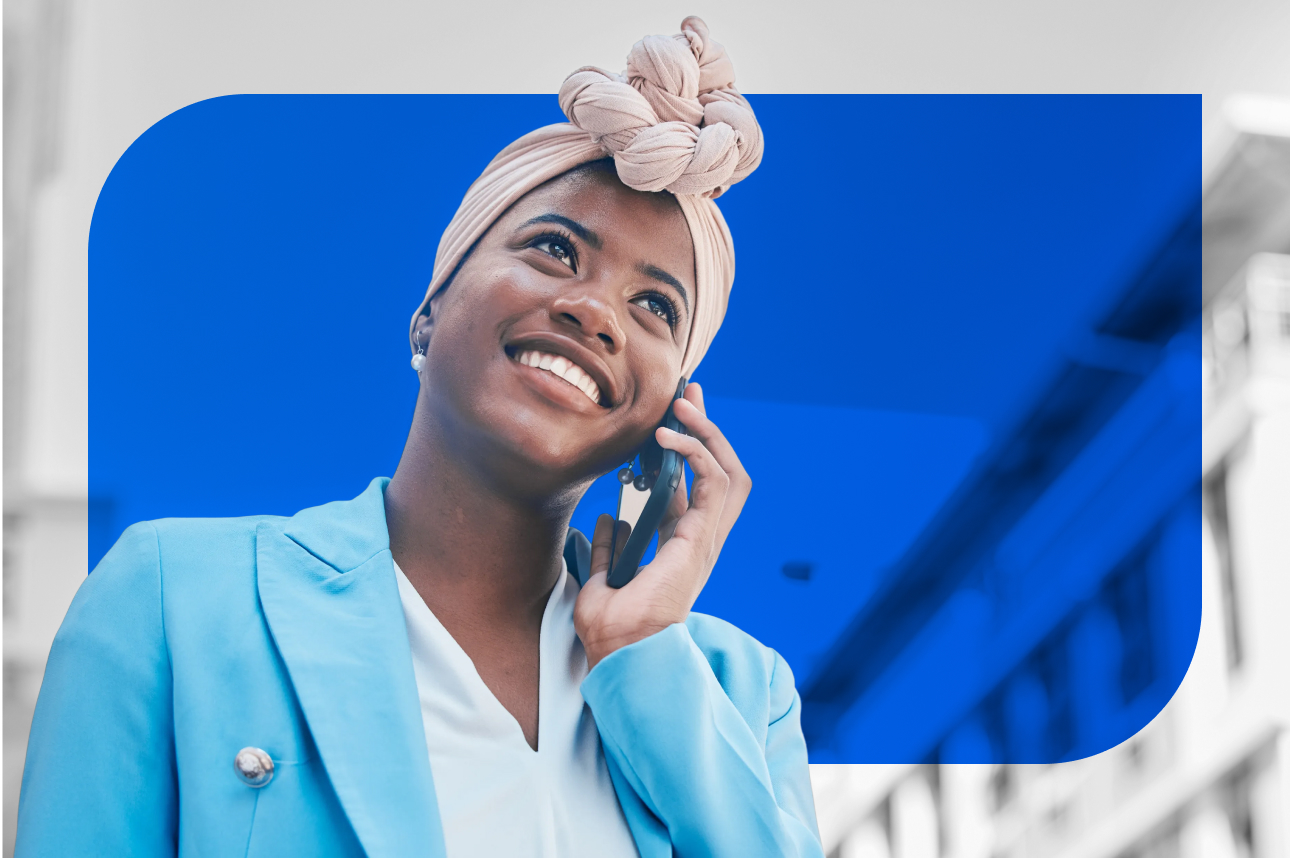 Smiling woman in blue blazer talking on phone against blue background