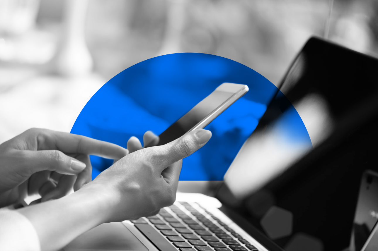 Hands using smartphone near laptop with blue circular background
