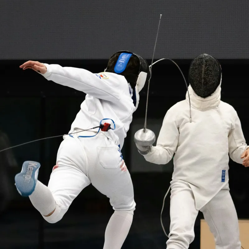 Ice hockey player wearing white and blue gear skating on an outdoor rink at sunset.