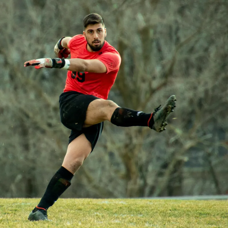 Woman dressed in white equestrian attire standing next to a white horse in a dimly lit indoor setting.