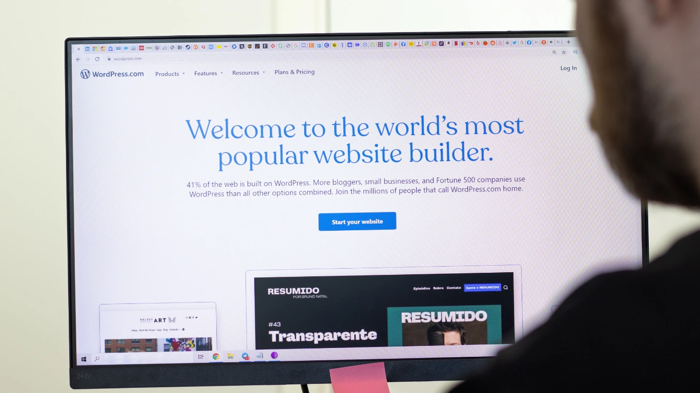 Professional looking at the WordPress platform homepage on a desktop monitor