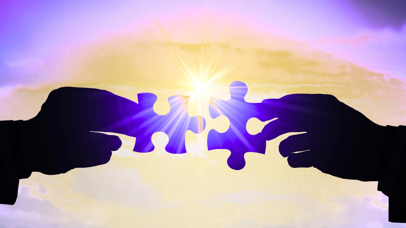Two silhouetted hands holding glowing purple puzzle pieces together against a bright light background, representing business partnerships