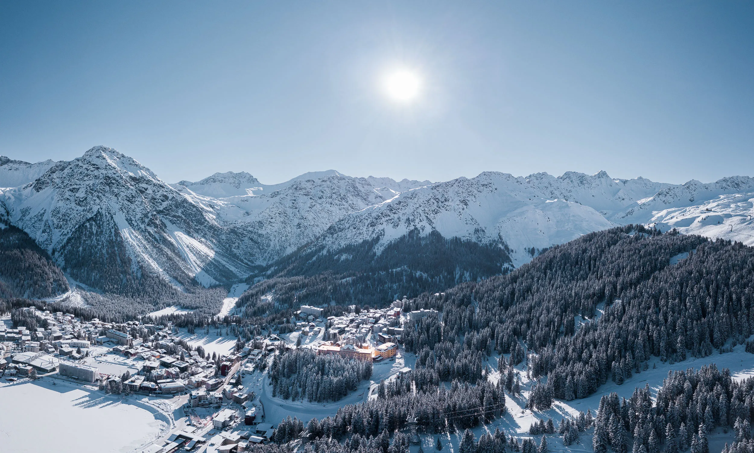 Schneebedeckte Berge und ein ruhiges Arosa in den Alpen unter klarem, strahlendem Himmel.