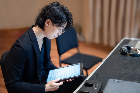 zhi looking down on his ipad containing the music he composed