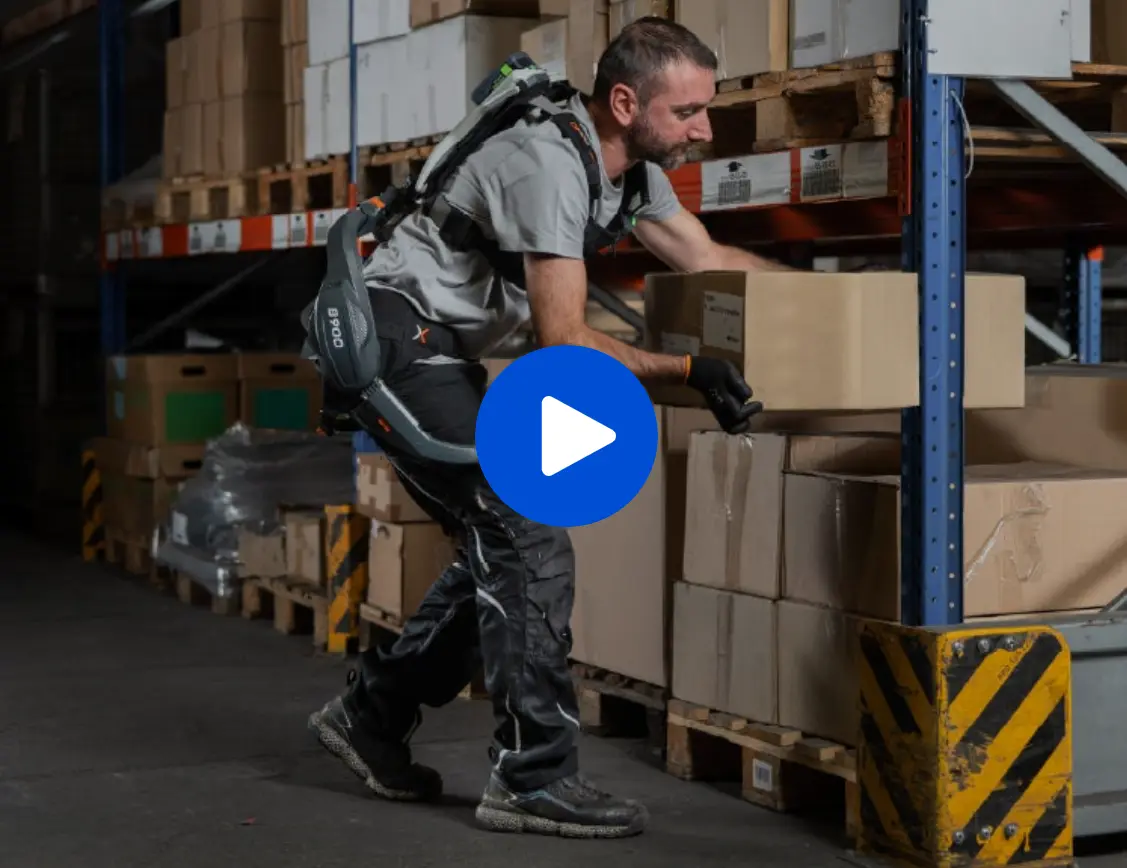 Video screenshot: A man wearing an exoskeleton is stacking boxes