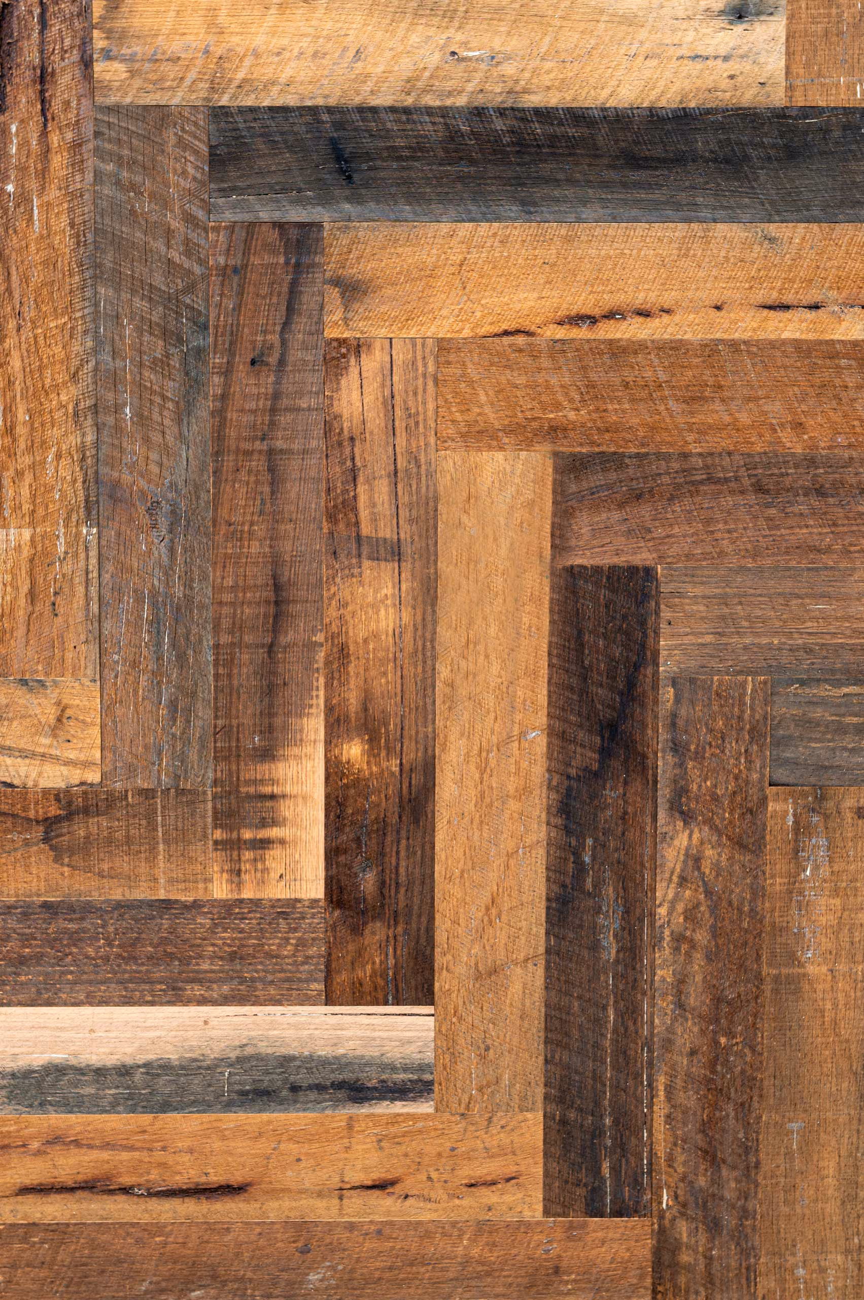 Close-up of a recycled engineered rough-sawn wood surface showing interlocking rectangular wood pieces in various brown tones and natural wood grain textures.
