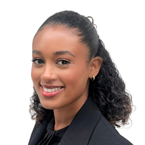 Smiling woman with curly hair tied back, wearing a black blazer and small hoop earrings.
