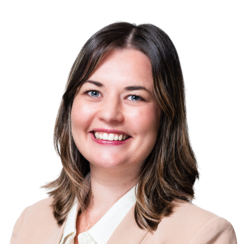 Smiling woman with shoulder-length brown hair wearing a beige blazer and white blouse.