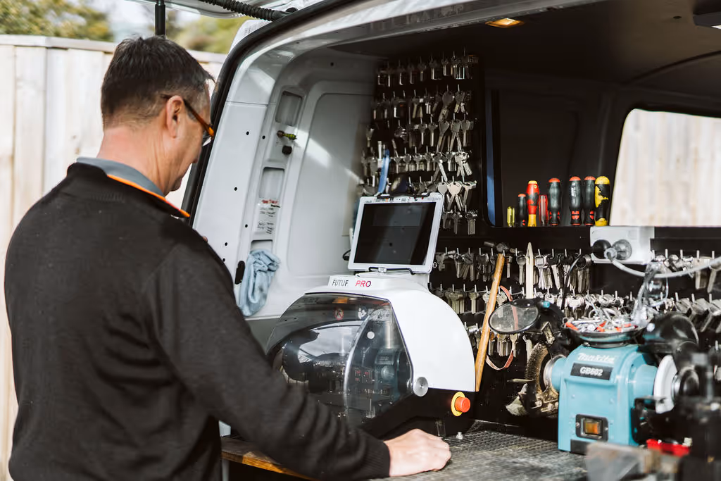 Technician working with key cutting machine in well-organized workshop van