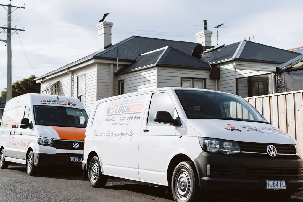 Two white Locksmith vans parked in front of a residential house