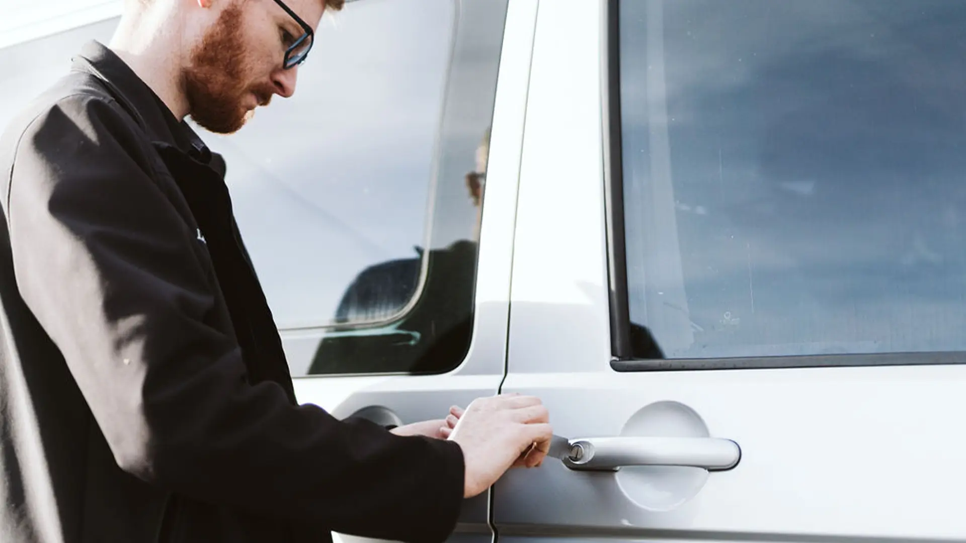 Person in black jacket opening white vehicle door