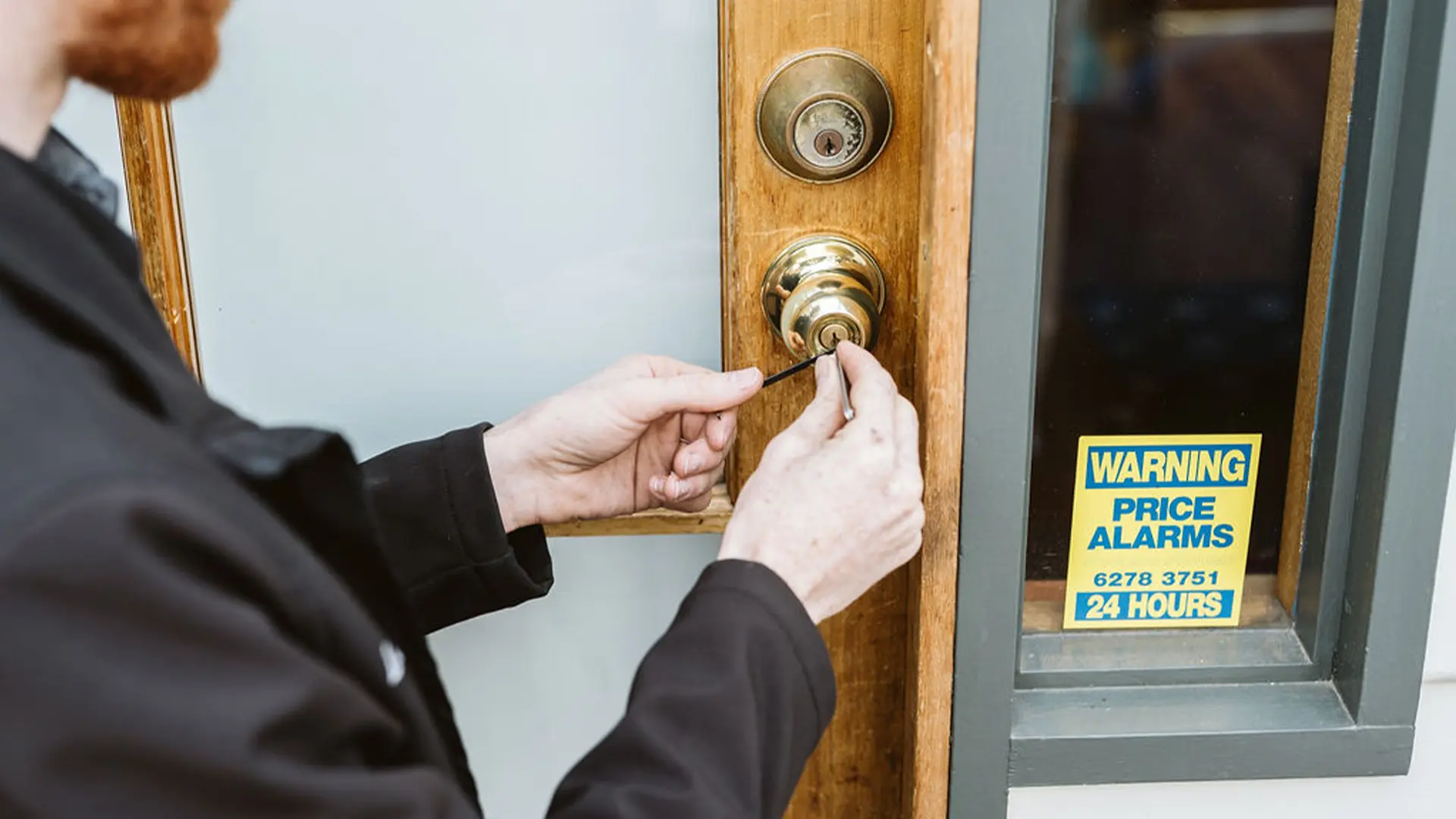 One of our licensed emergency locksmiths unlocking the front door of a suburban house after the homeowner forgot their key.