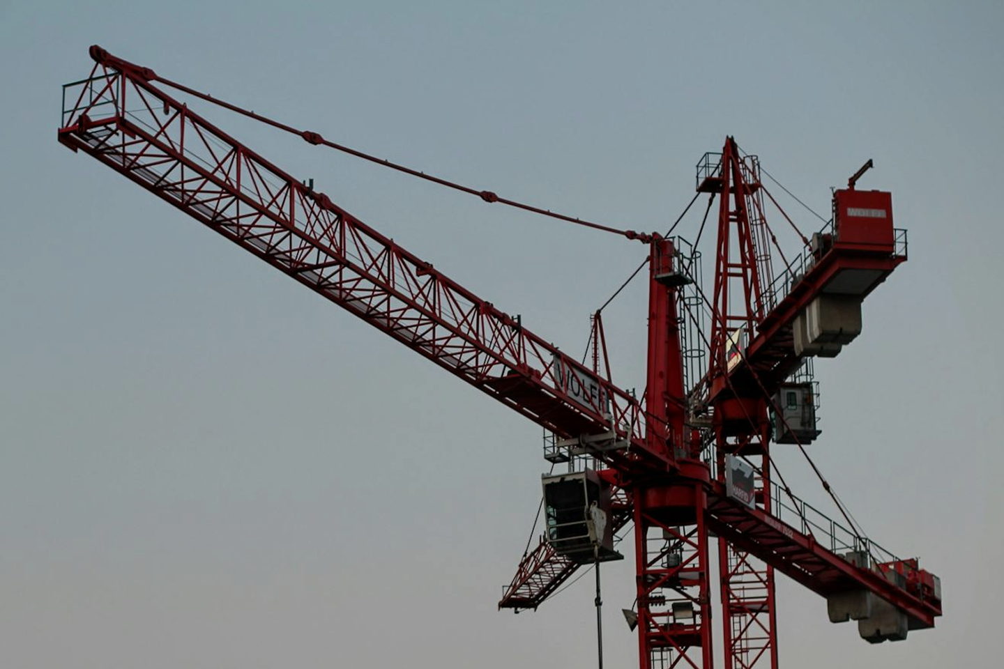 Red construction tower crane against a clear sky.