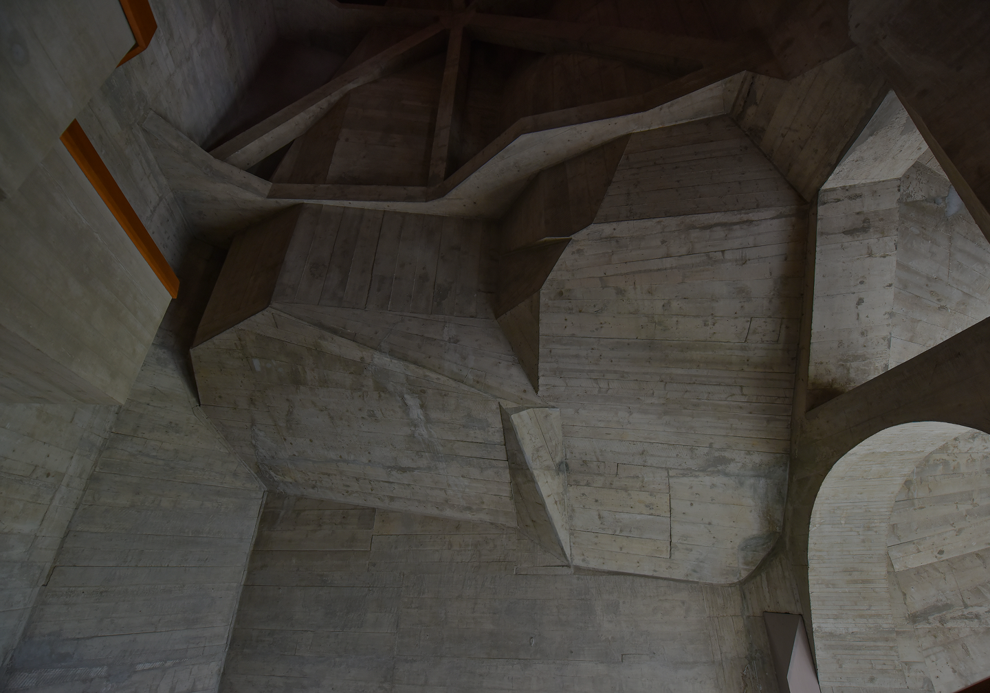 Complex geometric concrete ceiling structure with sharp angles and various planes.
