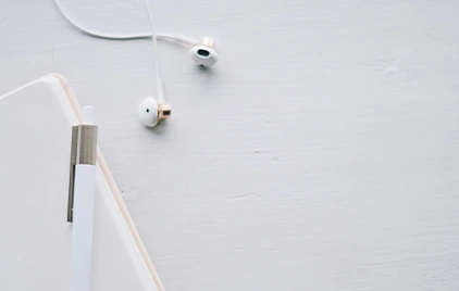 An earphone a pen and smartphone in white setting.