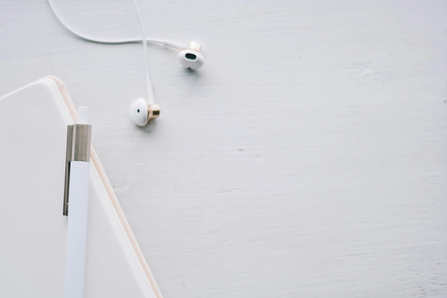 An earphone a pen and smartphone in white setting.