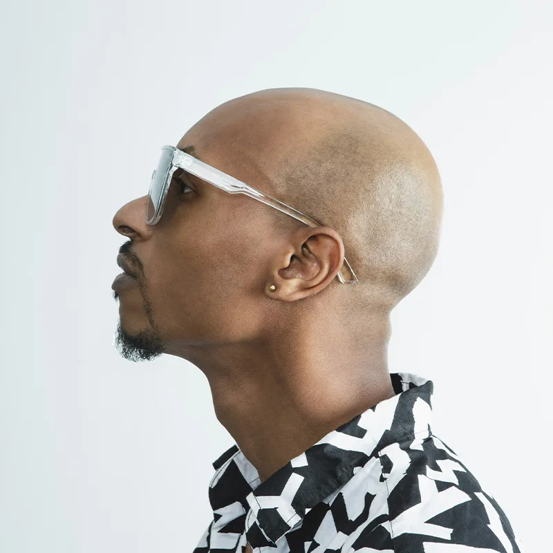 Side profile portrait of a bald man wearing patterned shirt.