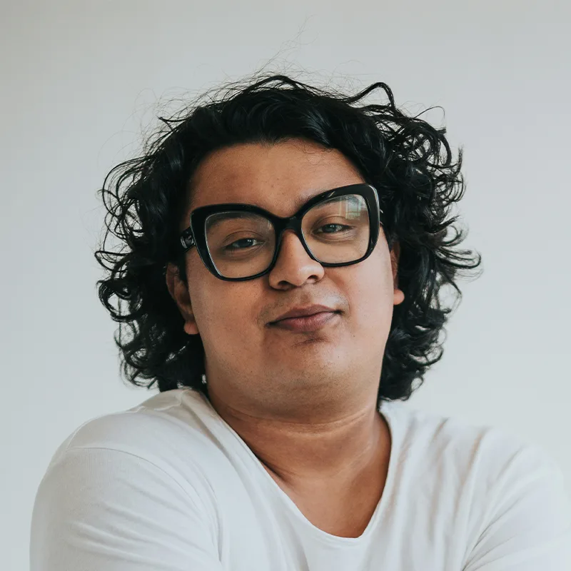 Portrait of a man with curly hair and glasses smiling.