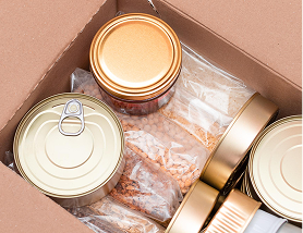 Cardboard box containing sealed canned goods and plastic bags with dried food items.