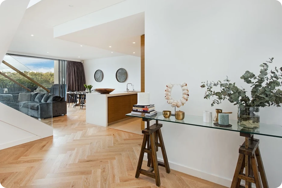 Modern kitchen with black cabinetry, striped rug, white upper cabinets, and bench seating by large window.