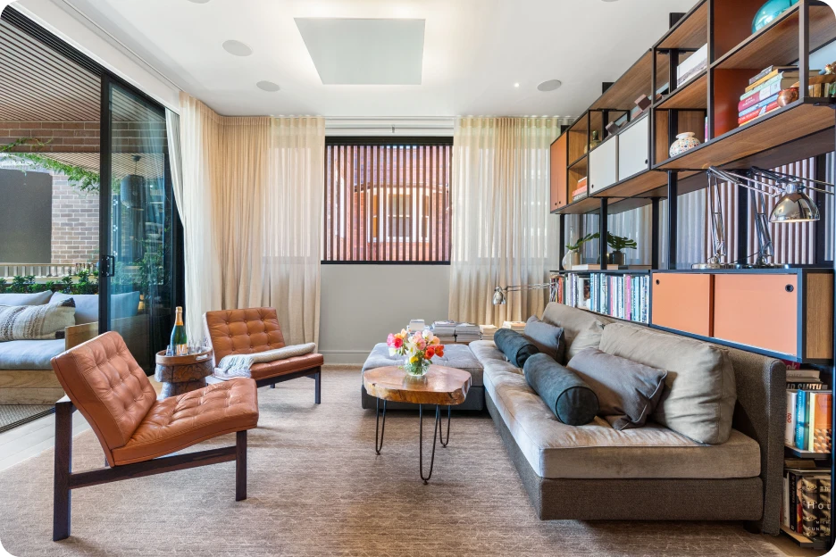 Modern living room with grey sofa, glass coffee table, large windows, city skyline view, and TV.
