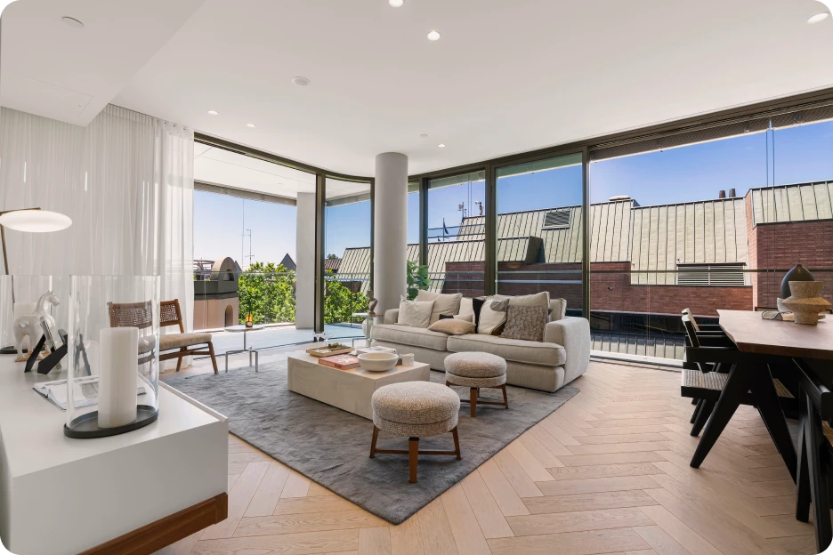 Modern living room with two leather chairs, a grey sofa, wooden shelving, and a sliding glass door.