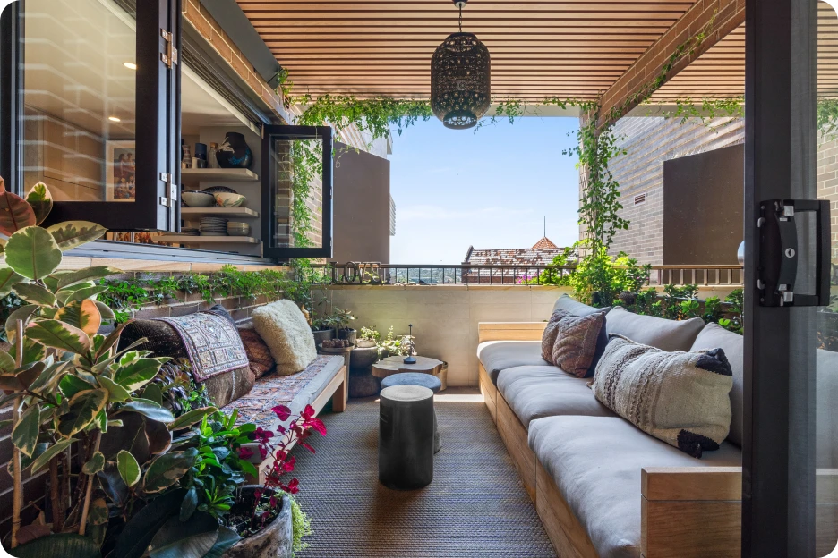 Modern open-plan lounge with wooden floor, grey sofa, red chairs, wooden table, and stairs to upper level