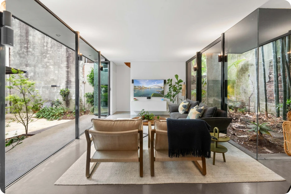 Modern living room with leather chairs, a patterned rug, bookshelves, and a fireplace with pear painting.