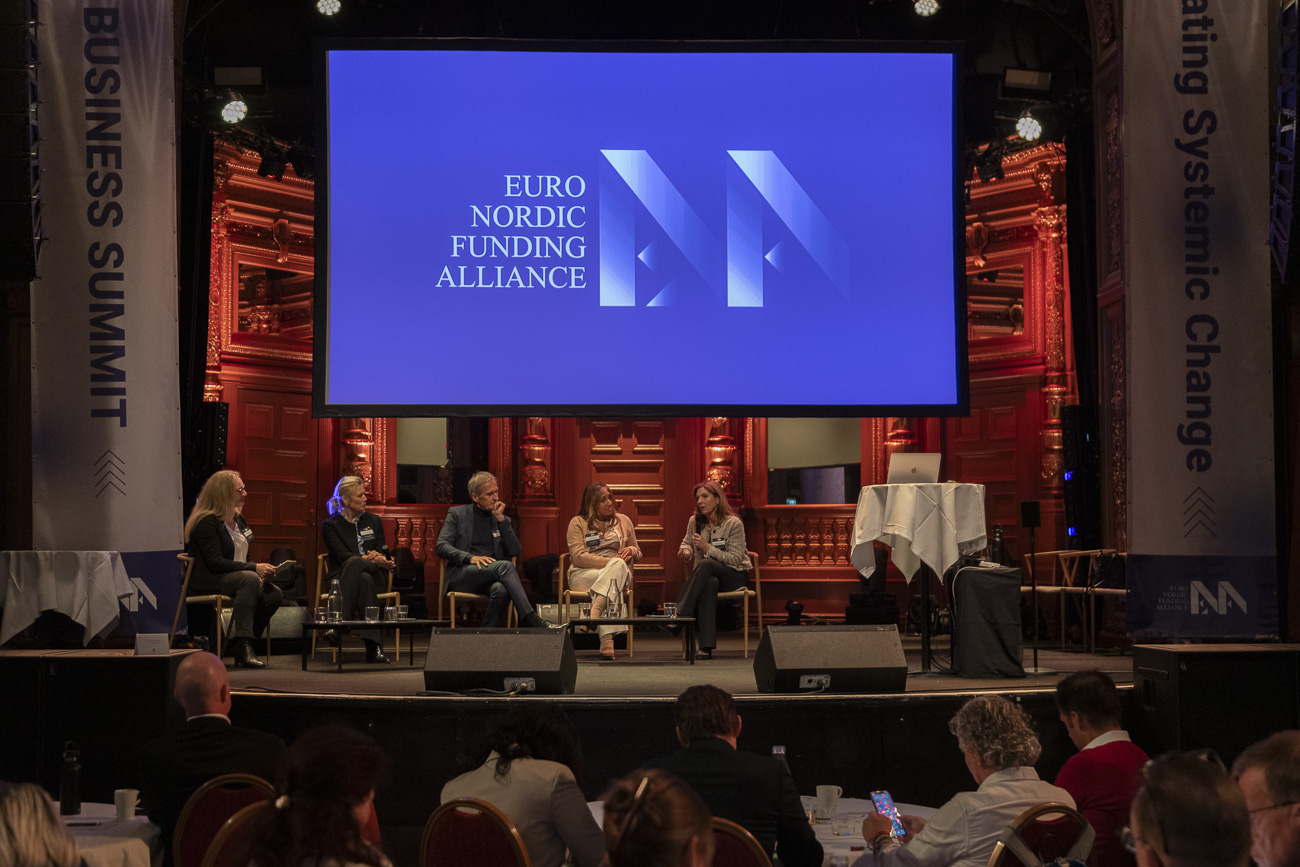 Panel of five speakers seated on stage at the Euro Nordic Funding Alliance business summit with attendees seated in foreground.