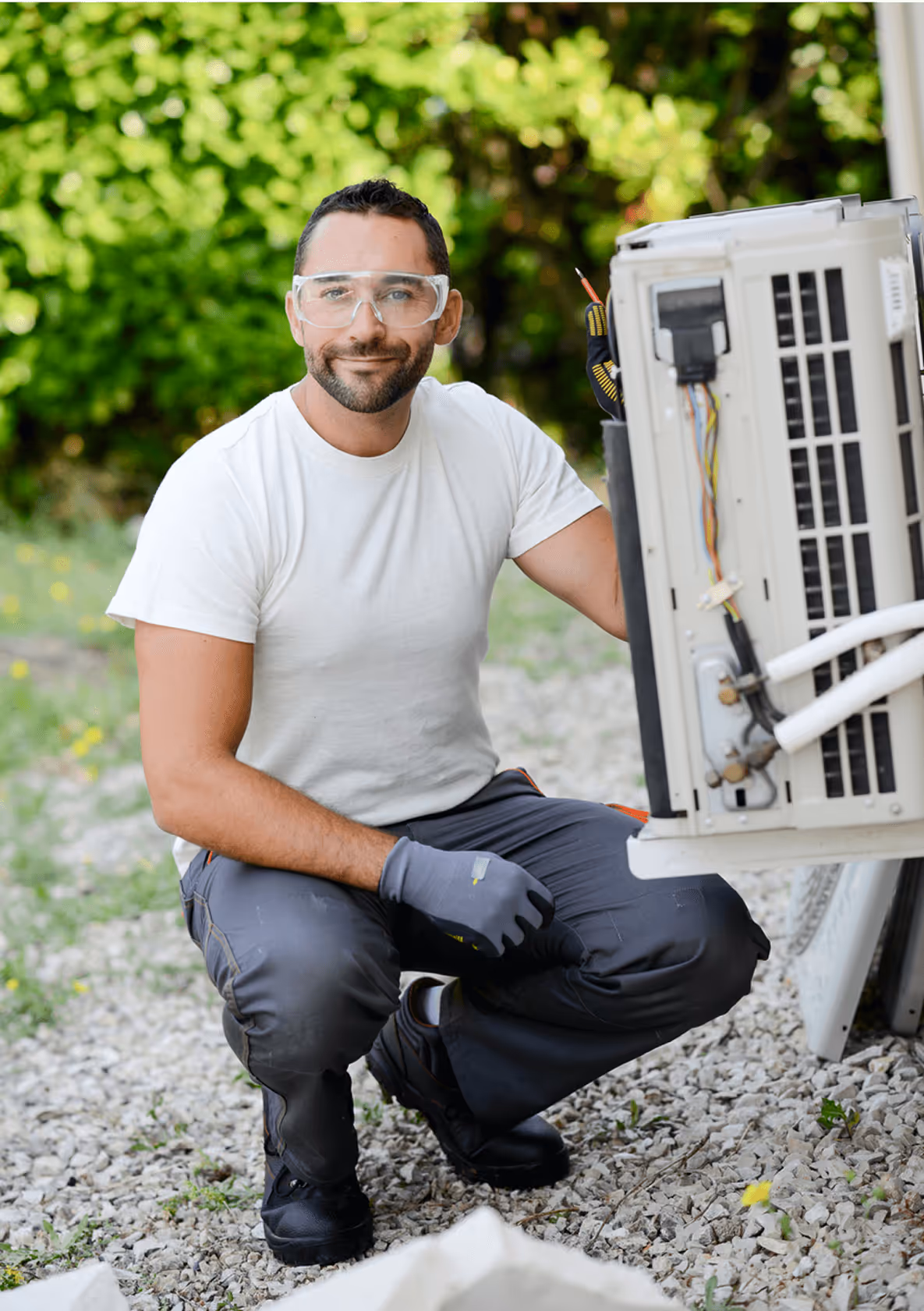Mann mit Schutzbrille und Handschuhen arbeitet an einer Klimaanlage im Freien.