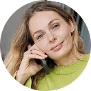 Frau in grünem Pulli telefoniert entspannt; blondes Haar, lächelt leicht.