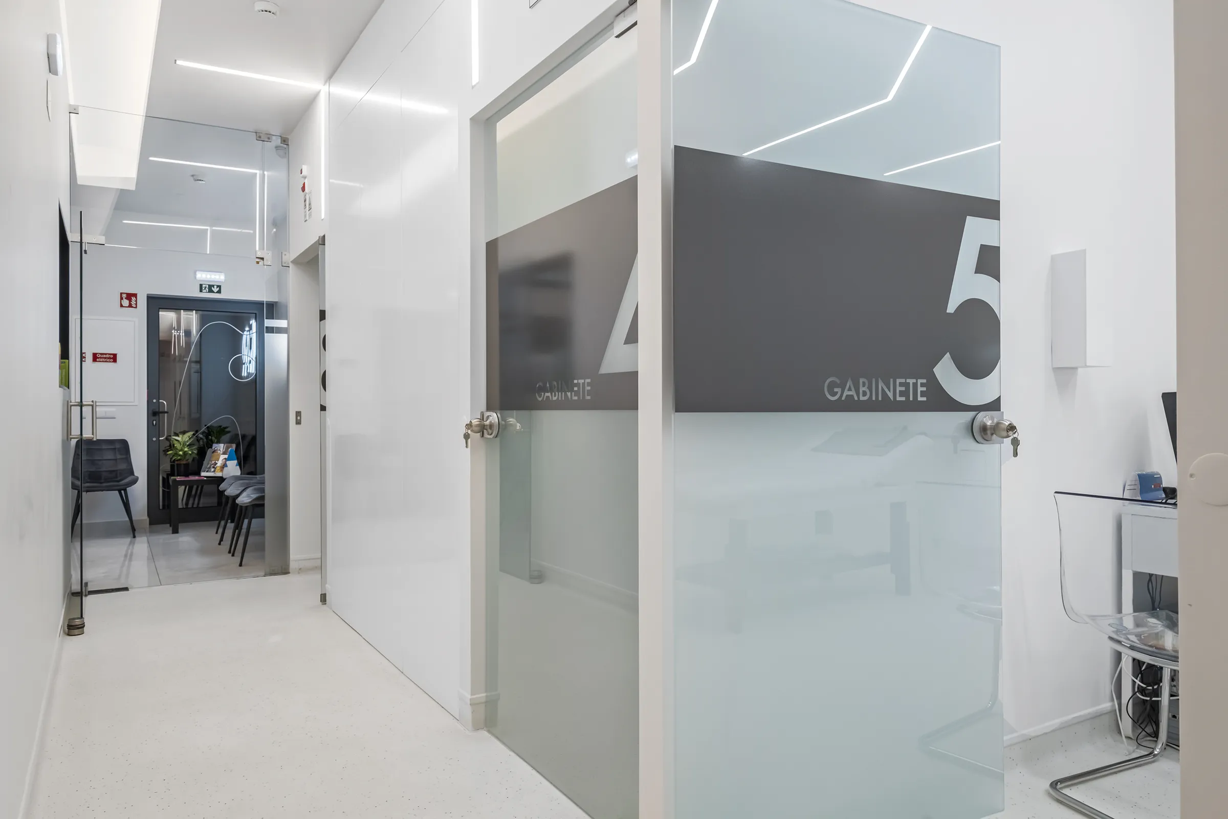Corredor da JAQ Clínica Dentária, branco moderno com portas de vidro fosco.