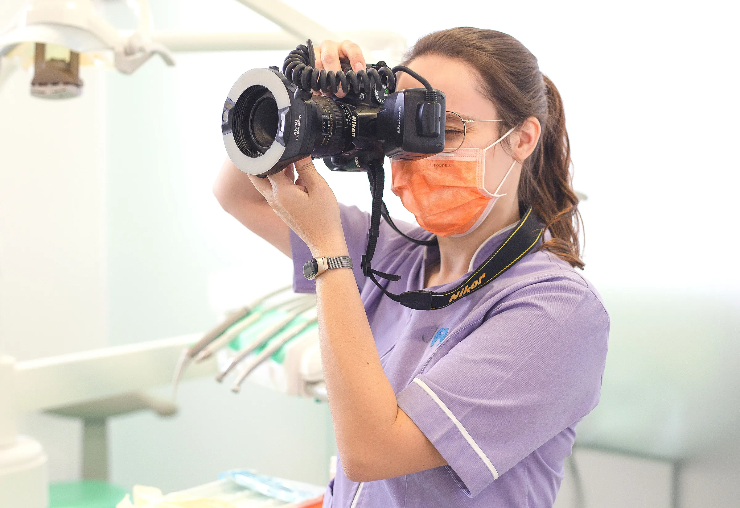 Médica dentista com máquina fotográfica a captar resultados do procedimento.