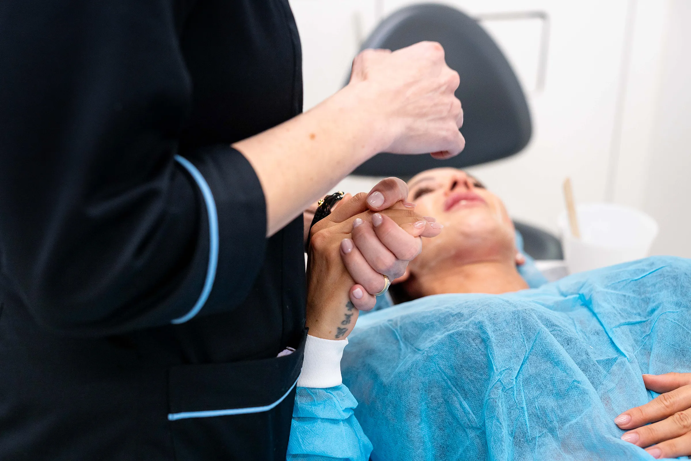 Profissional de saúde segura a mão de um paciente durante o procedimento médico.
