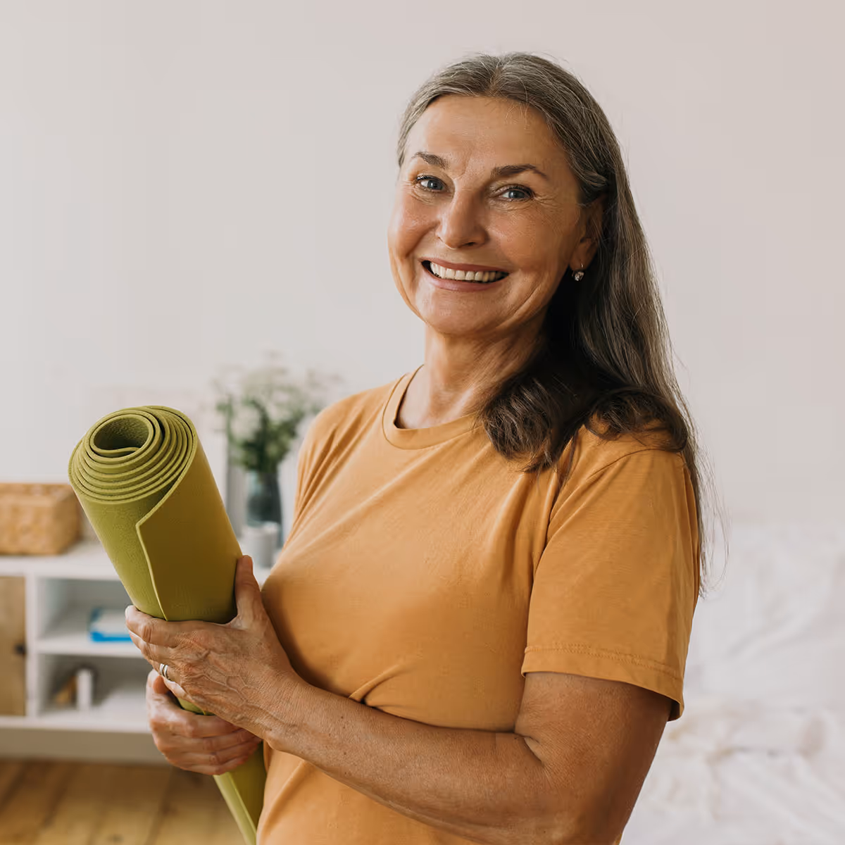 Mature woman looking energized holding rolled up yoga mat