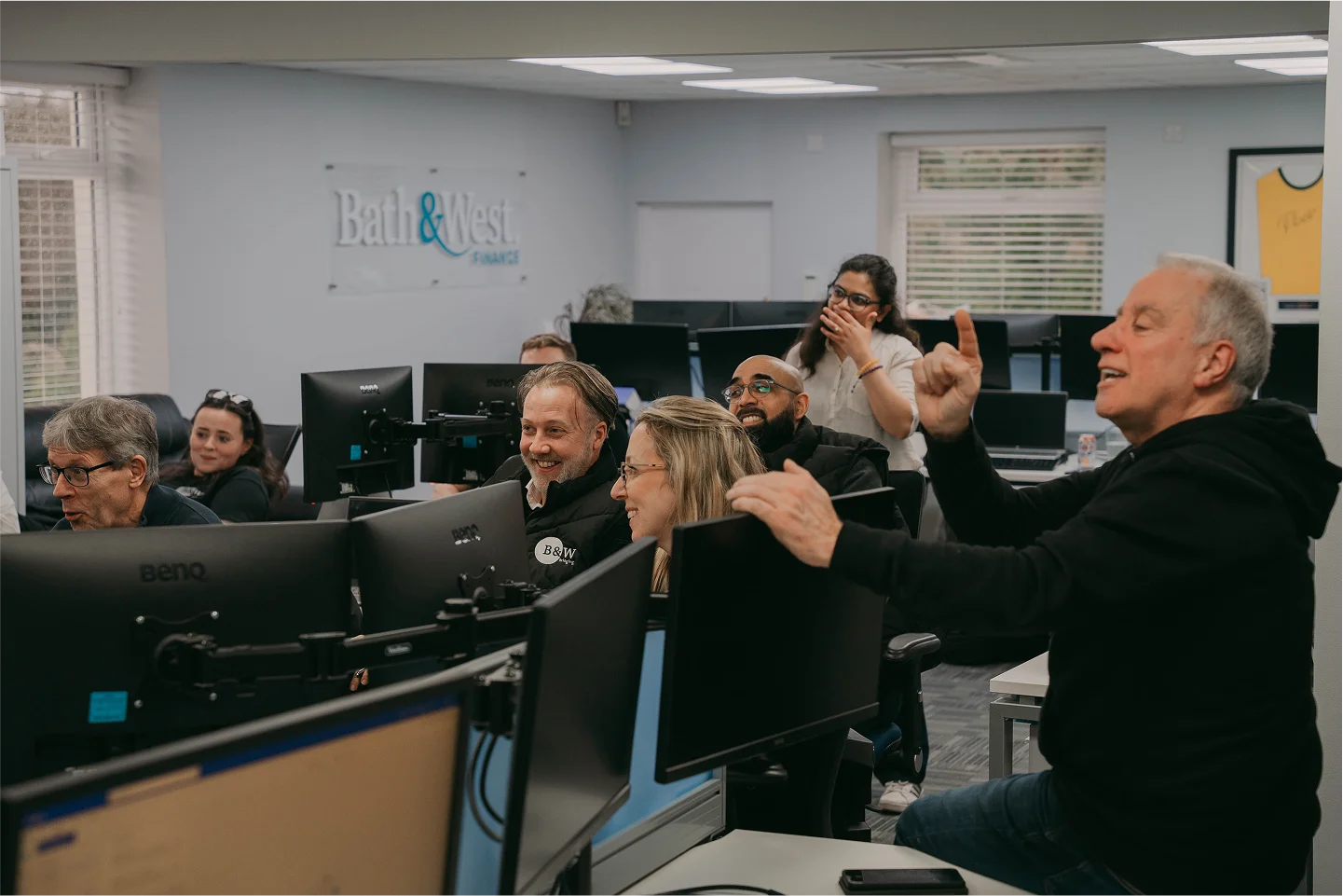 Martyn, the CEO laps as the team laugh and smile during a team catch up in the main offices of Black and White Bridging.