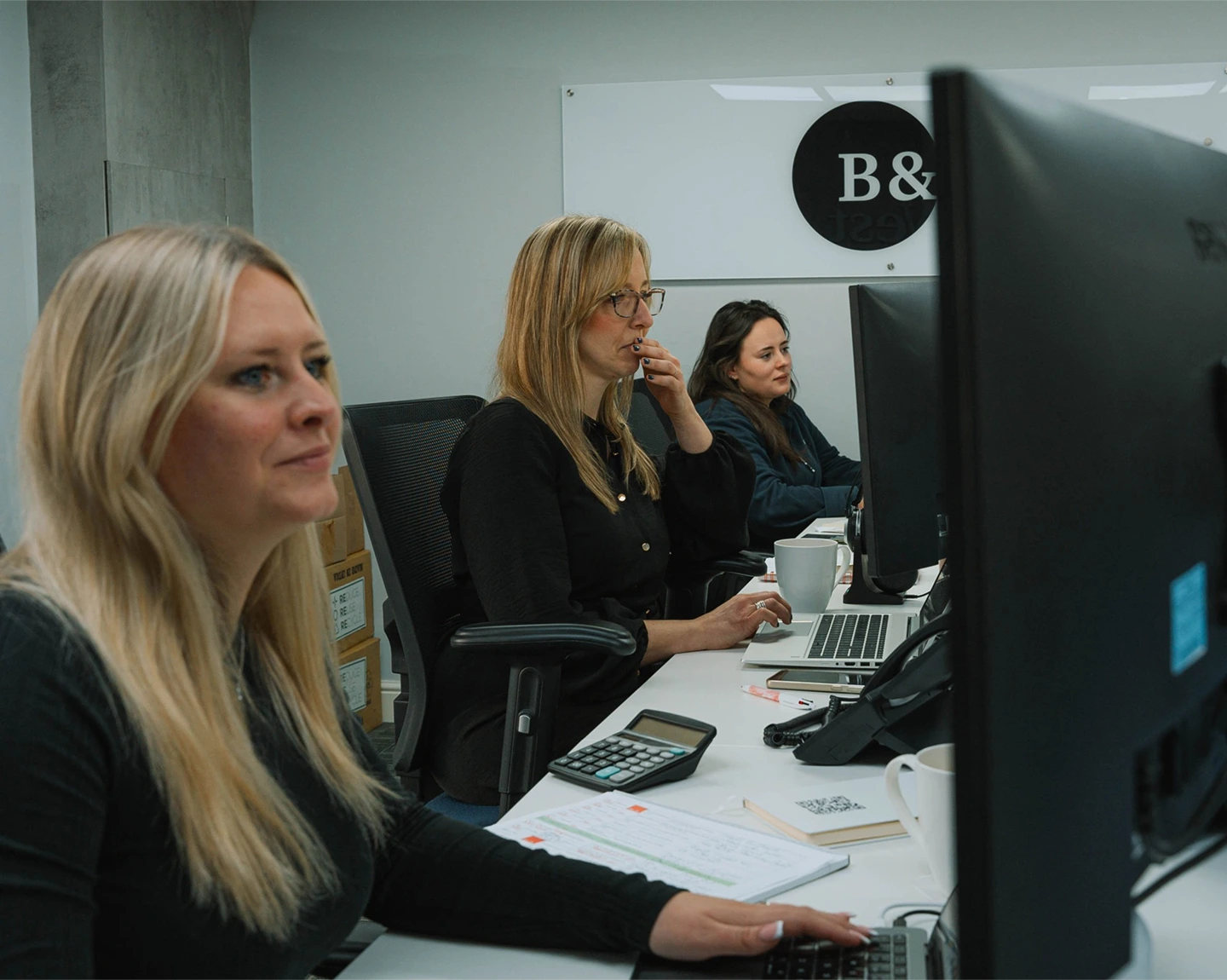 Suze, Heather and Jess responding to client enquiries in the Black and White Bridging office.