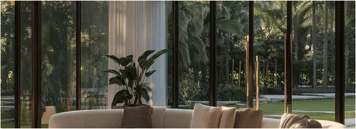 Modern living room with large windows overlooking lush tropical garden