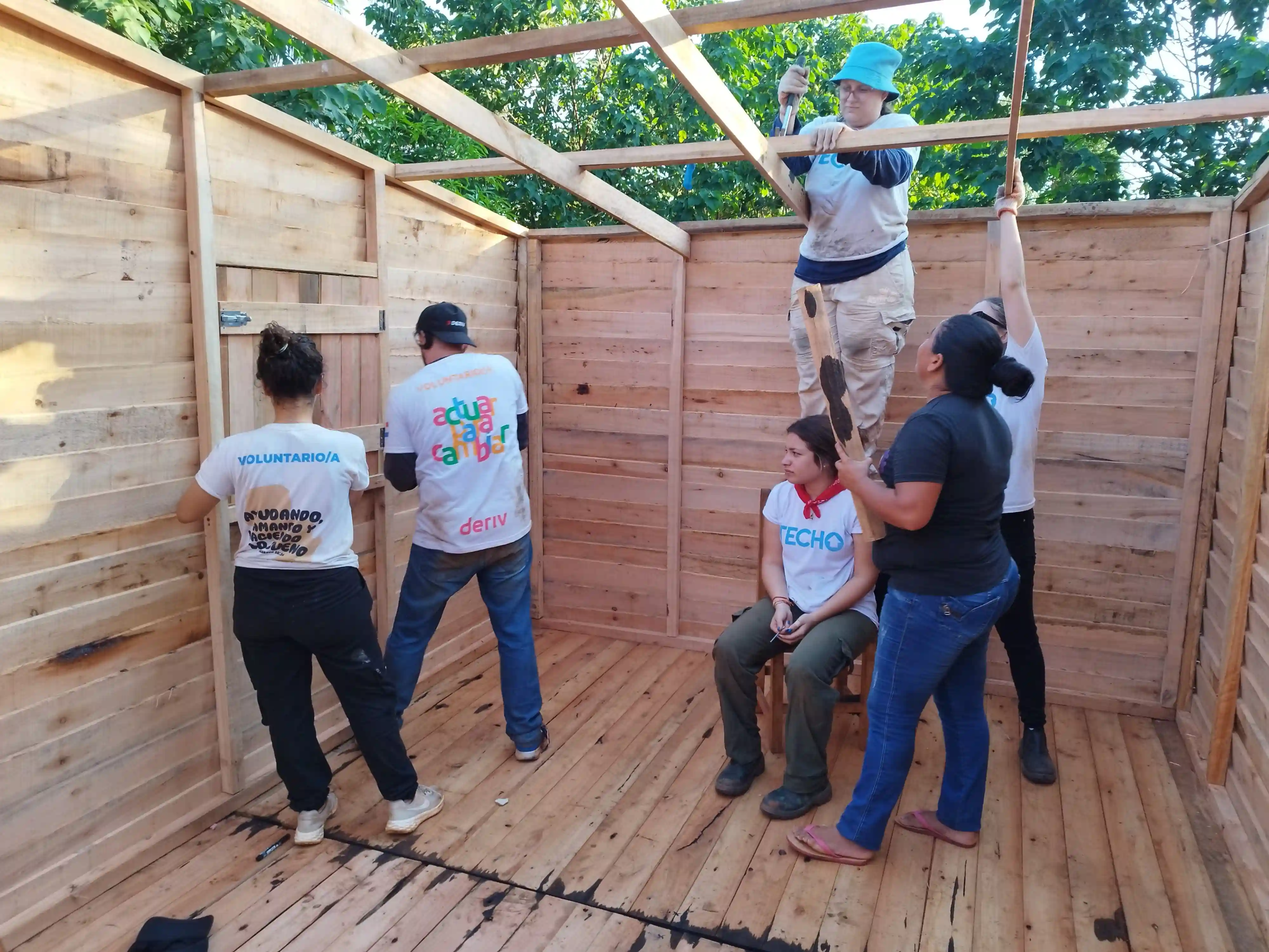 Volunteers construct a wooden structure, reflecting Deriv’s commitment to building resilient communities through skill-based support.