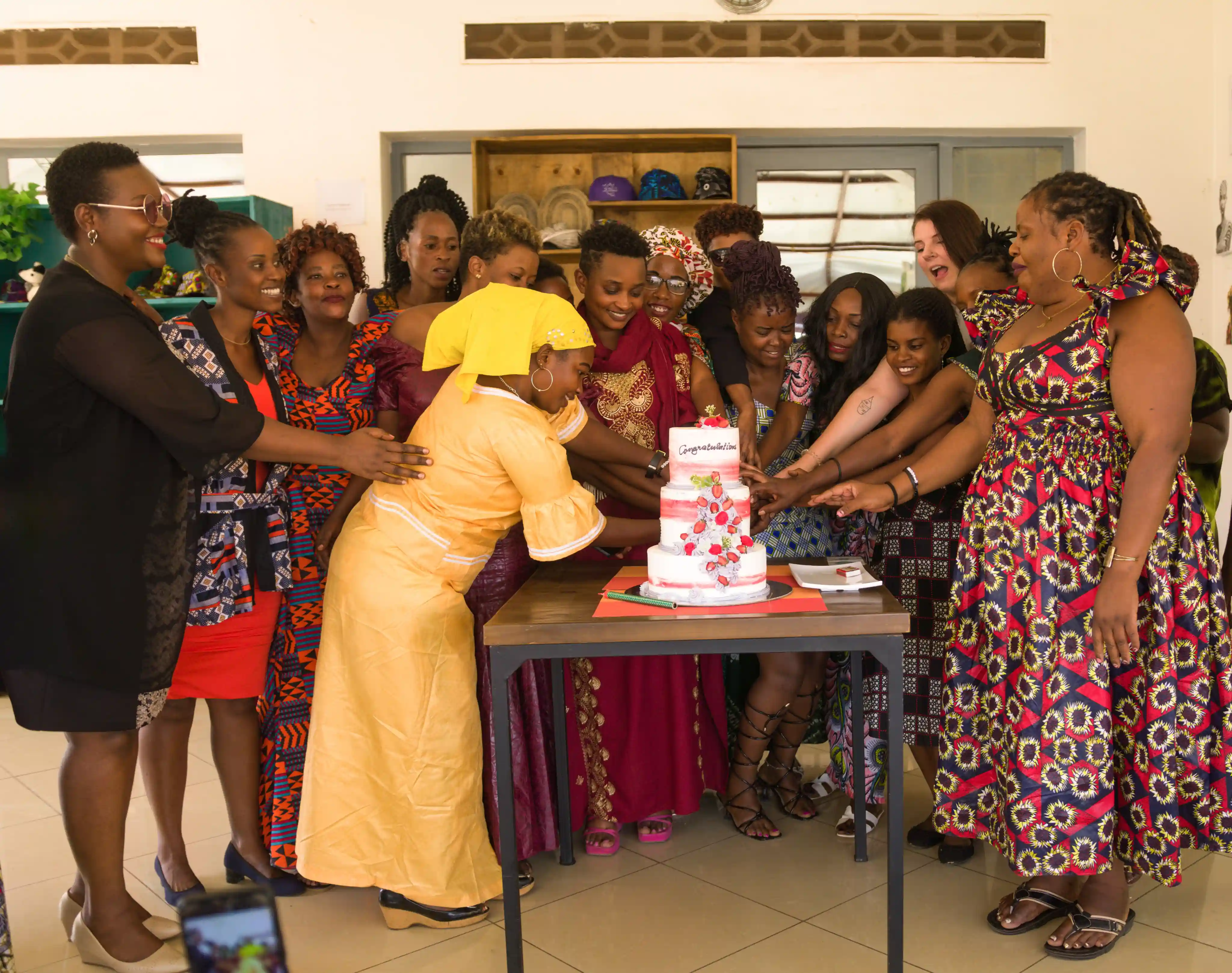 A group of women celebrate around a cake, symbolizing empowerment through education, mentorship, and career development support.