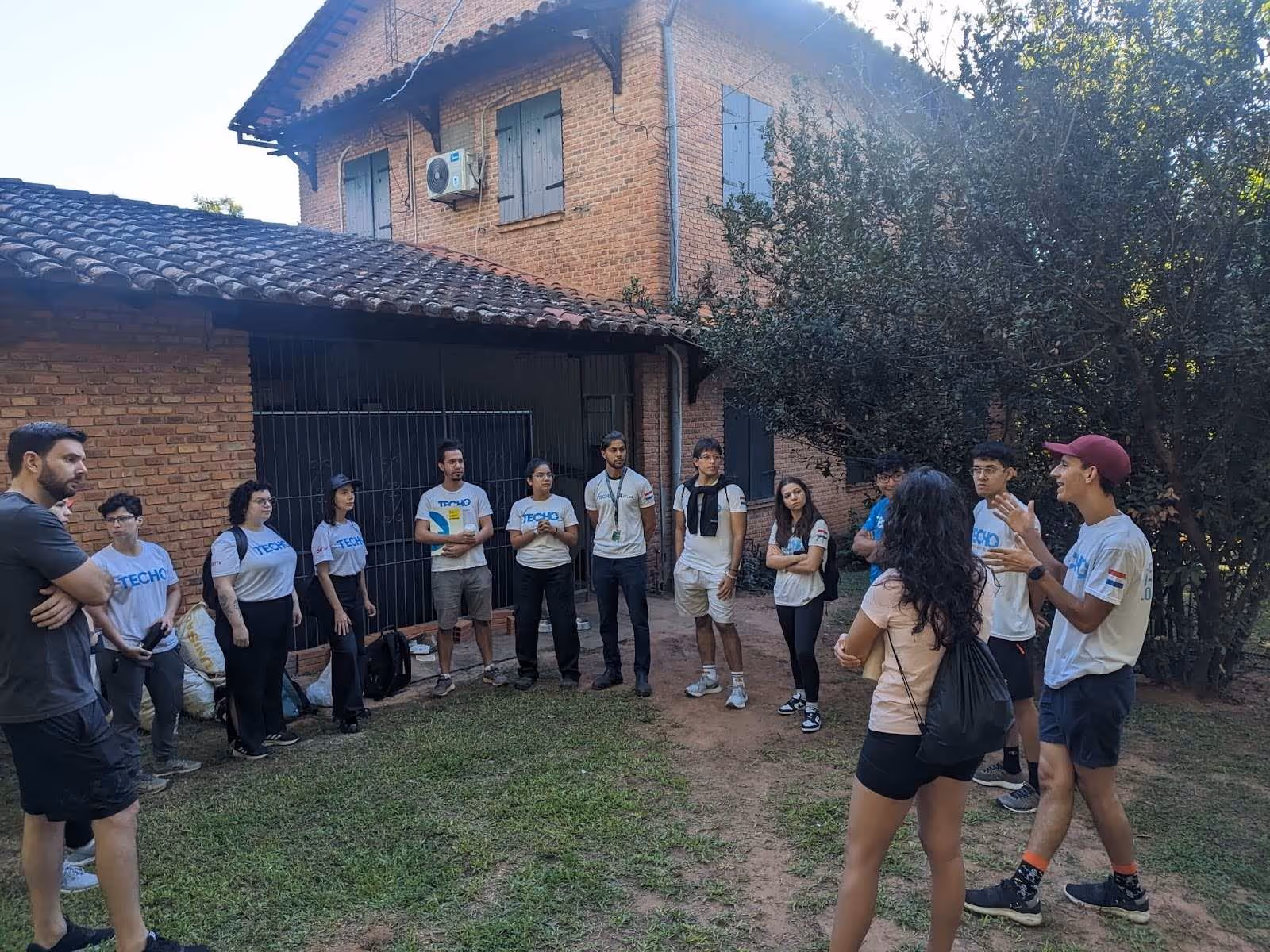 Deriv Asunción and TECHO teams forming a circle while discussing the CSR initiative.