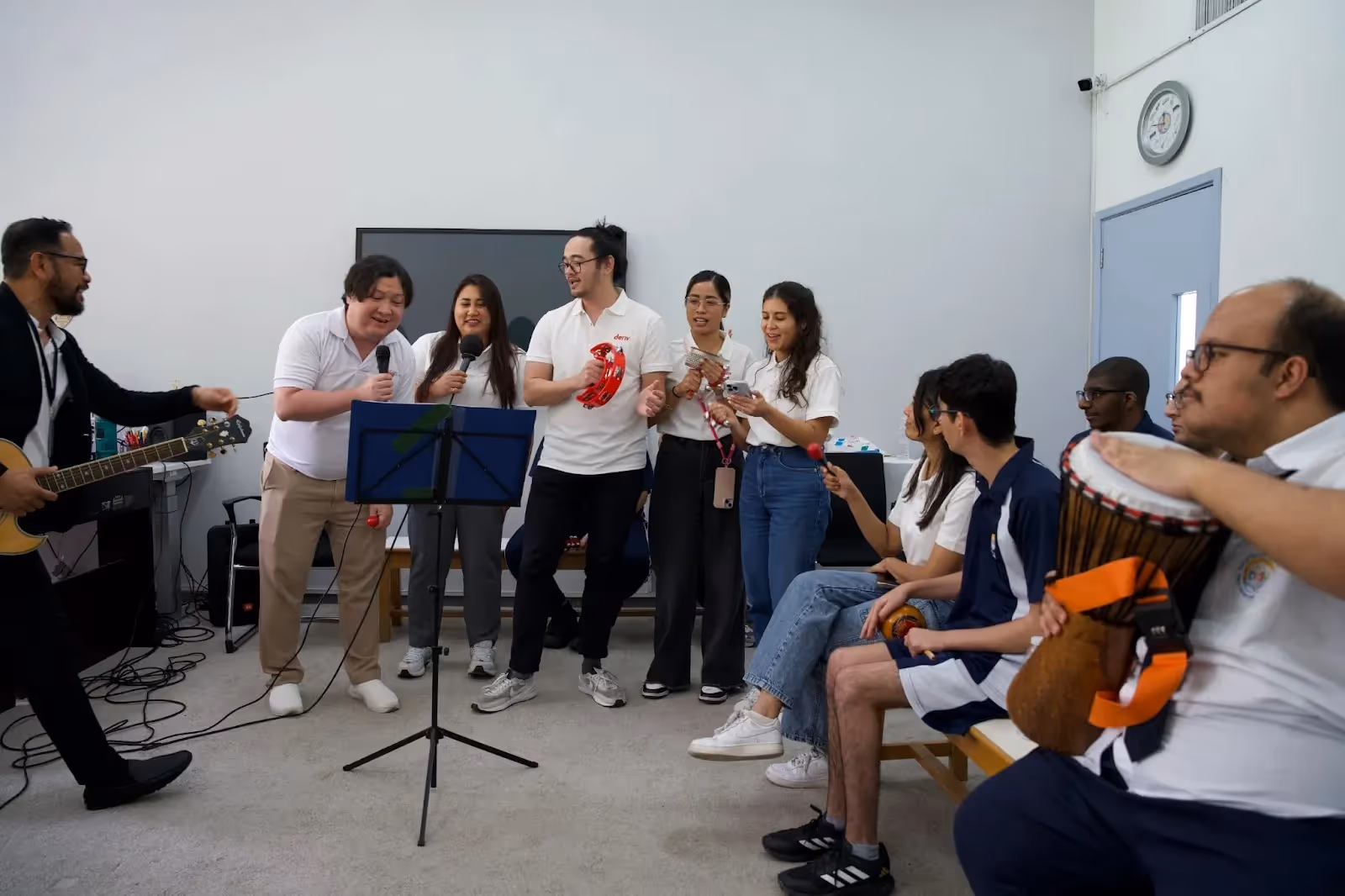  Deriv volunteers and DCSN students singing together and playing music.